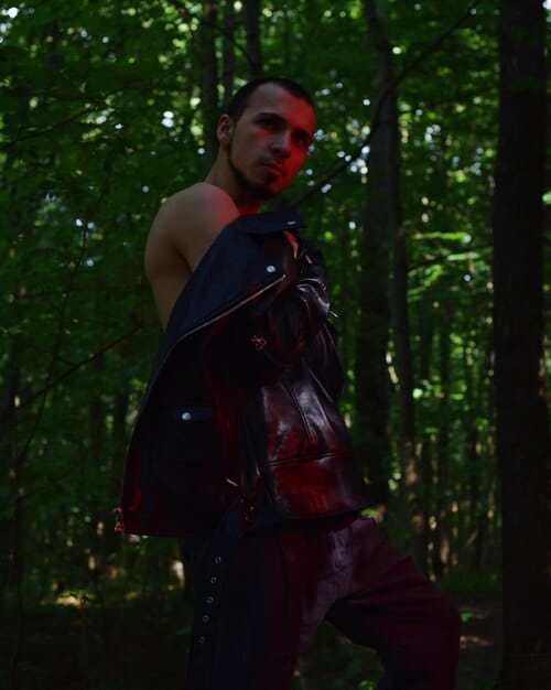 Liam Hemsworth in costume as Geralt of Rivia, walking through a misty forest setting, with a serious expression on his face, evoking the solitary nature of the character.