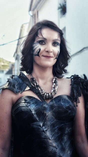 Close-up shot of Anya Chalotra as Yennefer, displaying a determined and slightly burdened expression. Her eyes reflect the flickering candlelight of a dimly lit room, suggesting the weight of her responsibilities in rebuilding Aretuza. Focus on her resolute gaze and the subtle signs of weariness on her face.