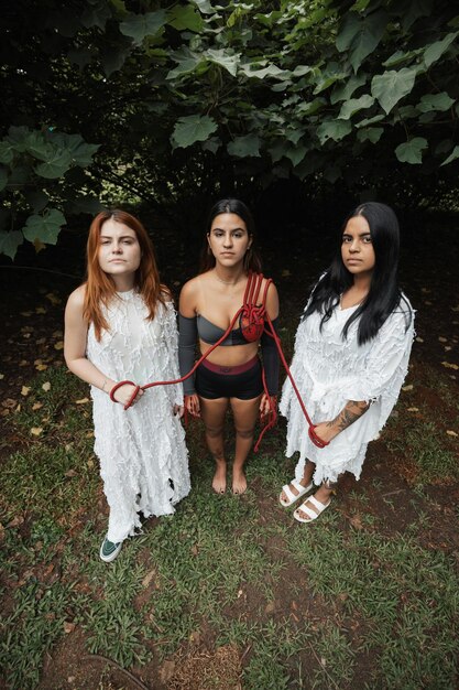 A group shot of Anya Chalotra as Yennefer, Freya Allan as Ciri, and Joey Batey as Jaskier, standing together in a scene from a previous season of The Witcher. The image should highlight their camaraderie and the importance of their relationships to Geralt.