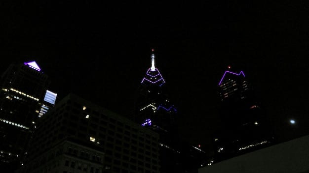 A panoramic view of a US city skyline at night, with a subtle overlay of The Witcher's logo, symbolizing the concert coming to these urban centers.