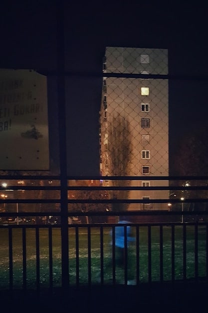 A historic hotel exterior at dusk, with a subtle overlay of spectral figures in the windows, creating an eerie and inviting atmosphere.