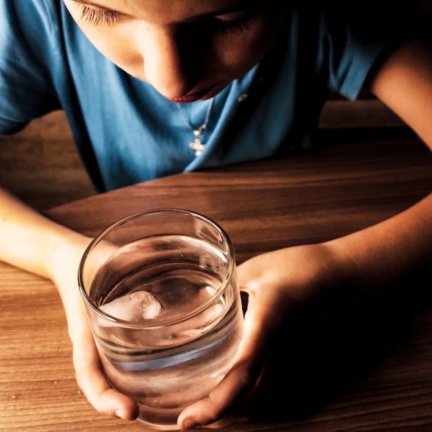 A person sitting in dim light, focusing on a bowl of water with their hands on either side of the bowl while looking into the water.