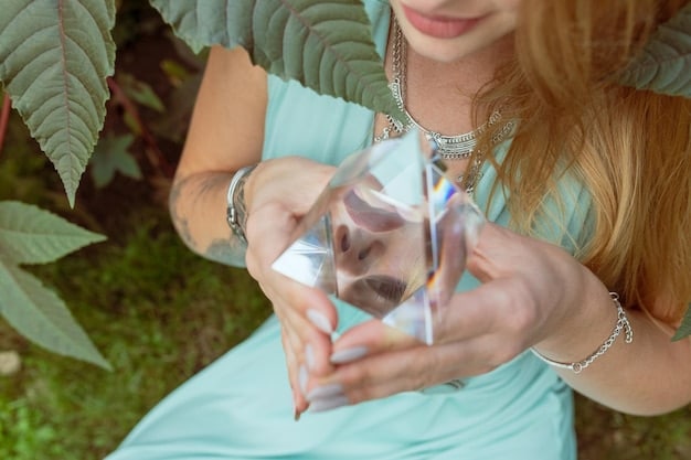 A hand holding a clear quartz crystal under running water from a faucet, symbolizing the water cleansing method. The water is clear and reflects light, and the hand is gently holding the crystal.