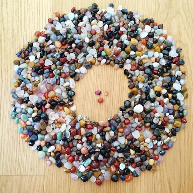 Overhead shot of crystals arranged in a circular pattern on a wooden surface. The crystals vary in color and size, creating a visually appealing and balanced display.