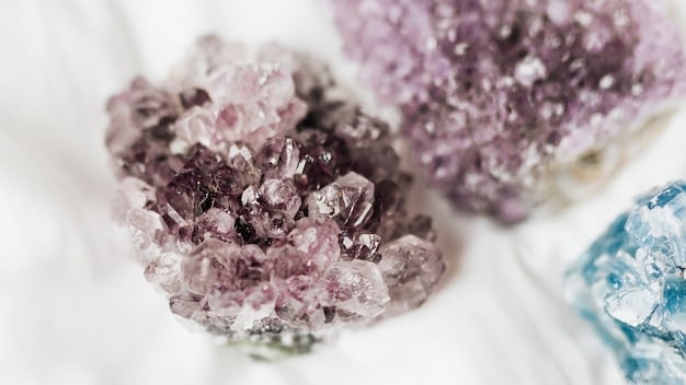 A close-up photograph showing a selection of crystals including clear quartz, amethyst, and rose quartz, arranged on a wooden surface with soft, diffused lighting, highlighting their natural beauty and textures.