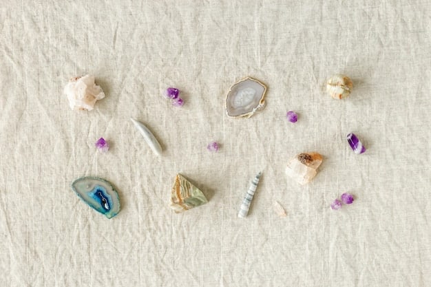 A selection of different colored crystals is laid out on a white cloth, each crystal labeled with its corresponding healing property for pain relief, such as amethyst for headaches and rose quartz for emotional pain.