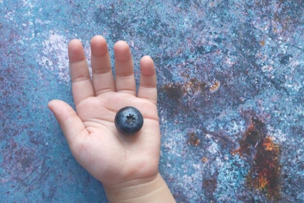 A close-up shot of a person's hand holding a black tourmaline crystal. The background is blurred, creating a sense of focus on the crystal's texture and color.