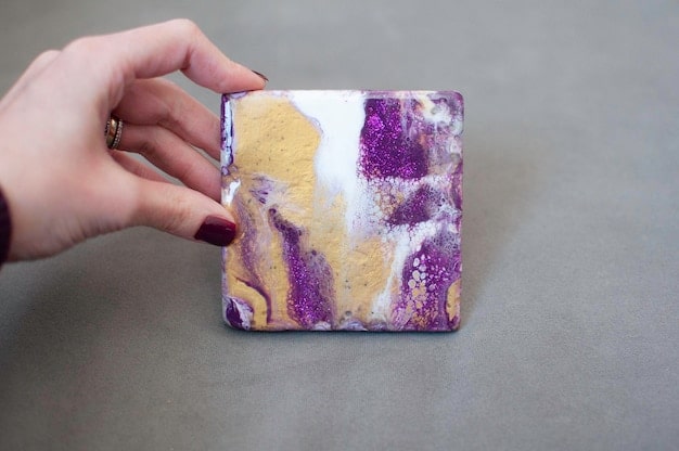 A hand holding a polished piece of lepidolite, displaying its layered, shimmering purple and lilac hues.