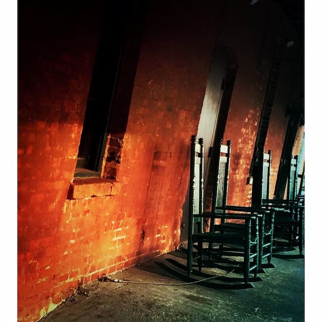 A dimly lit image inside an abandoned building with caution tape stretched across a crumbling doorway. An EMF meter is visible in the foreground, suggesting active paranormal investigation, juxtaposed with potential hazards. Symbolizes the balance between exploration and risk management.