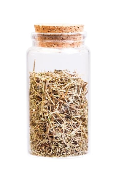 A clear glass jar filled with layered ingredients such as salt, dried herbs (rosemary, thyme), black peppercorns, and cloves. A handwritten label on the jar reads 