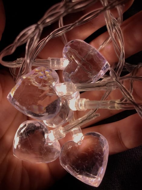 A close-up shot of a crystal grid being activated with a selenite wand. The grid is laid out on a silk cloth and features a central clear quartz point surrounded by smaller amethyst and lapis lazuli stones. The selenite wand is held just above the central quartz, directing energy into the grid. The focus is on the intentionality and ritualistic aspect of activating the crystal grid. Unlock powerful manifestation with these expert layouts showcased in the image.