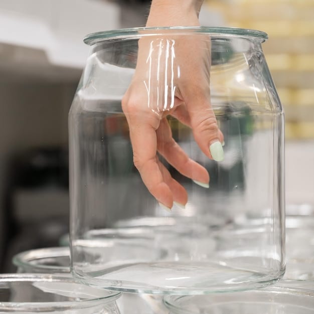 A person carefully placing a clear quartz crystal into a glass jar filled with water, using tongs to avoid direct contact. The jar is sitting on a clean, white countertop with soft natural light. The scene is focused on hygiene and safety. The purpose of crystal elixirs is to harness the energy of the crystal in the water in a safe way.