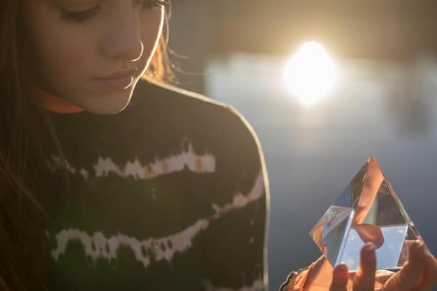 A person holding a clear quartz crystal point, with sunlight streaming through it. The background is softly blurred, highlighting the crystal's clarity and the focus of energy, demonstrating how to use crystal points for healing and intention setting in alignment with How to Choose the Right Crystal Shape for Maximum Healing in 2025.