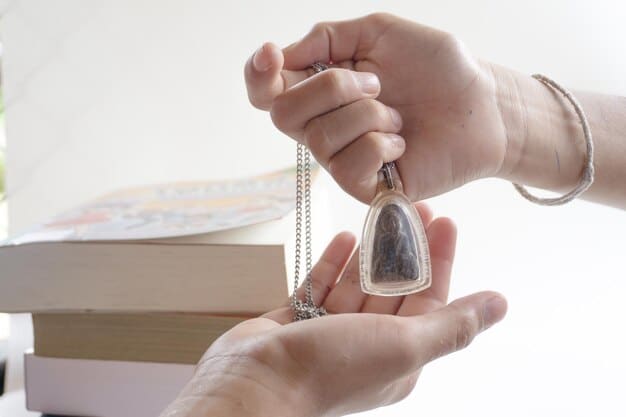 A person's hand gently holding a crystal pendulum over a question board or mat with 