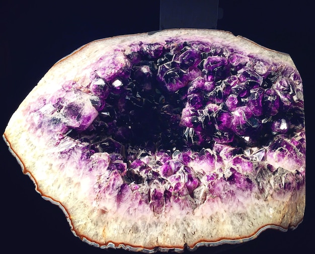 A geode of amethyst crystals, highlighting the deep purple color and crystalline structure. The geode is displayed in a museum setting, emphasizing its rarity and the scientific interest in crystal formations related to Investing in Crystals: A Guide to Identifying Authentic and High-Quality Stones.